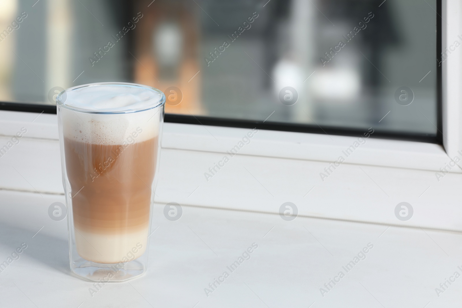 Photo of Glass with latte on white window sill. Space for text