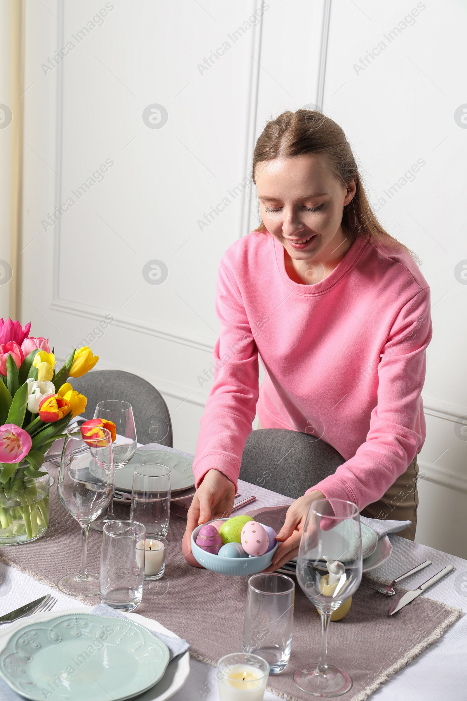 Photo of Woman setting table for festive Easter dinner at home