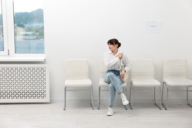 Photo of Woman sitting on chair and waiting for job interview indoors