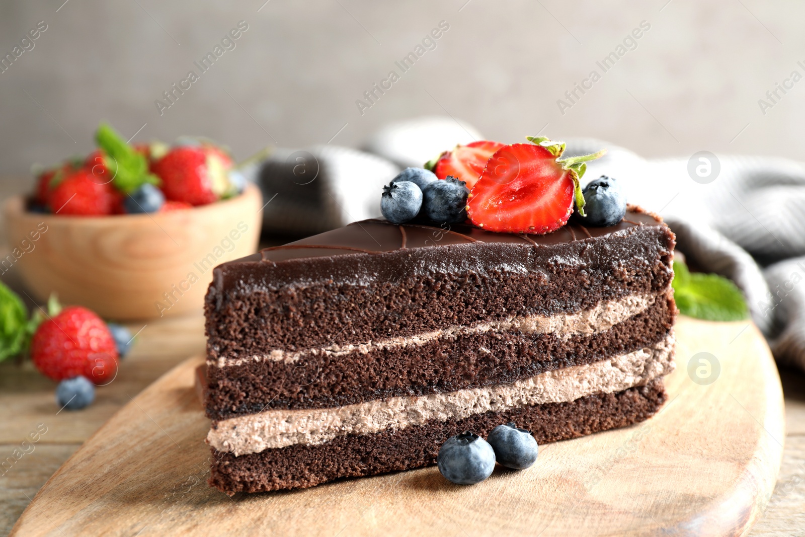 Photo of Delicious fresh chocolate cake with berries on wooden table, closeup