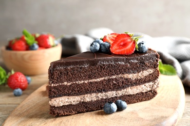 Photo of Delicious fresh chocolate cake with berries on wooden table, closeup