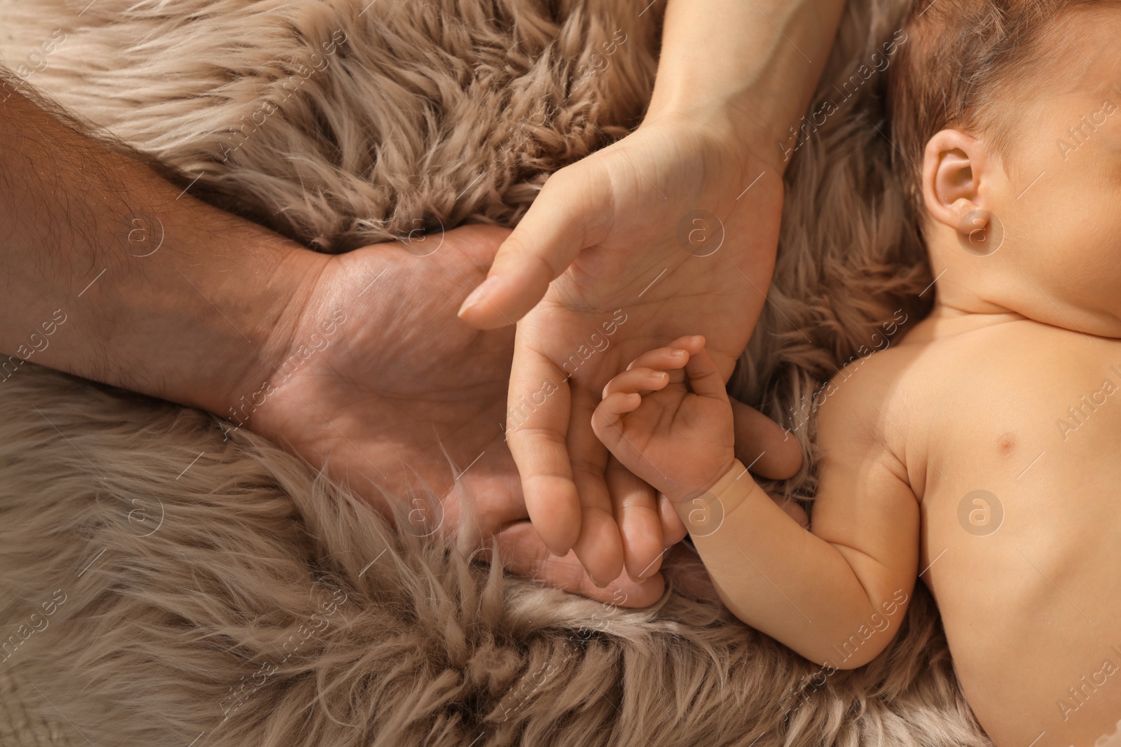 Photo of Mother and father with their newborn baby on fluffy blanket, top view. Lovely family