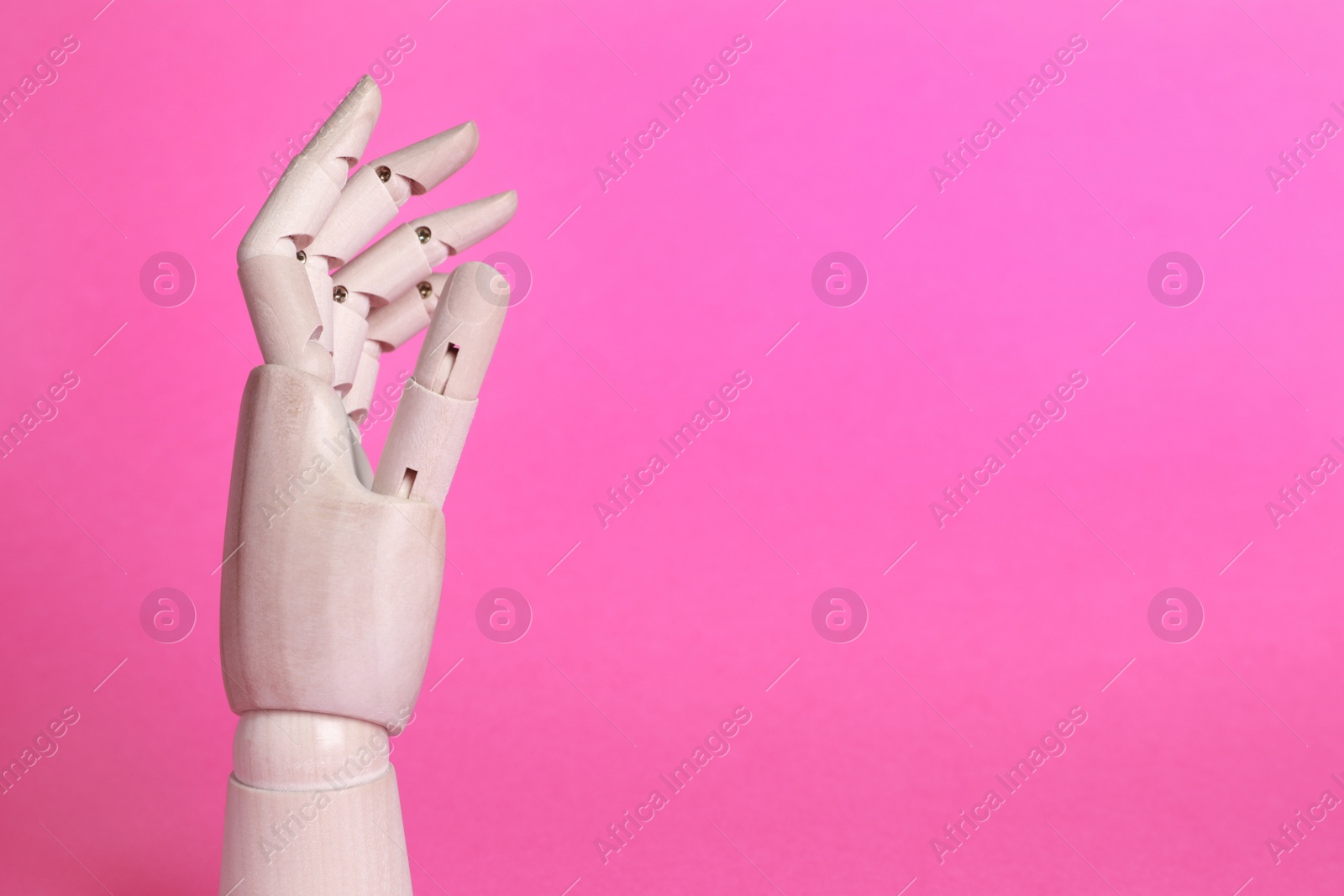 Photo of Wooden mannequin hand on pink background. Space for text