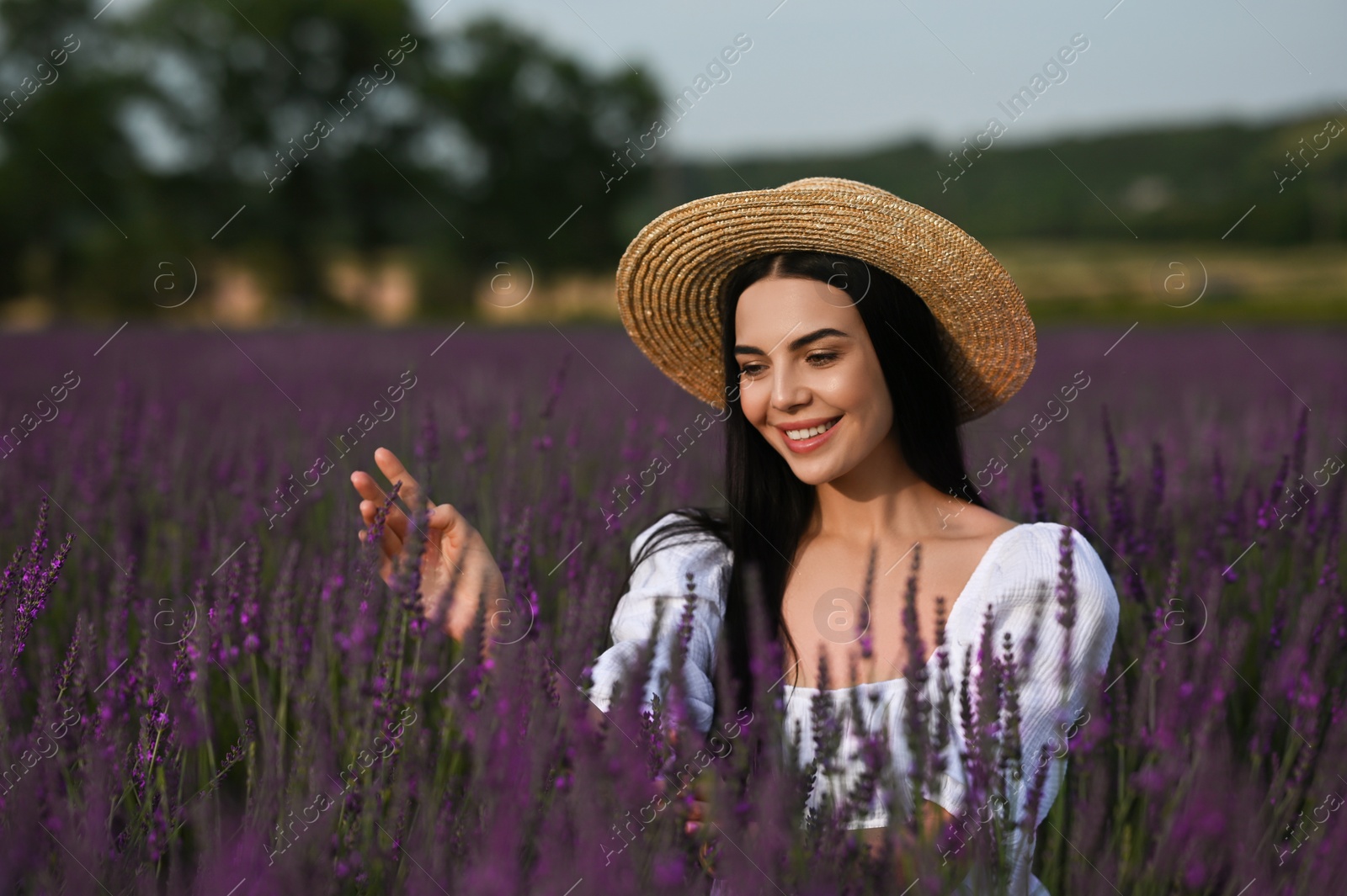 Photo of Beautiful young woman with straw hat in lavender field