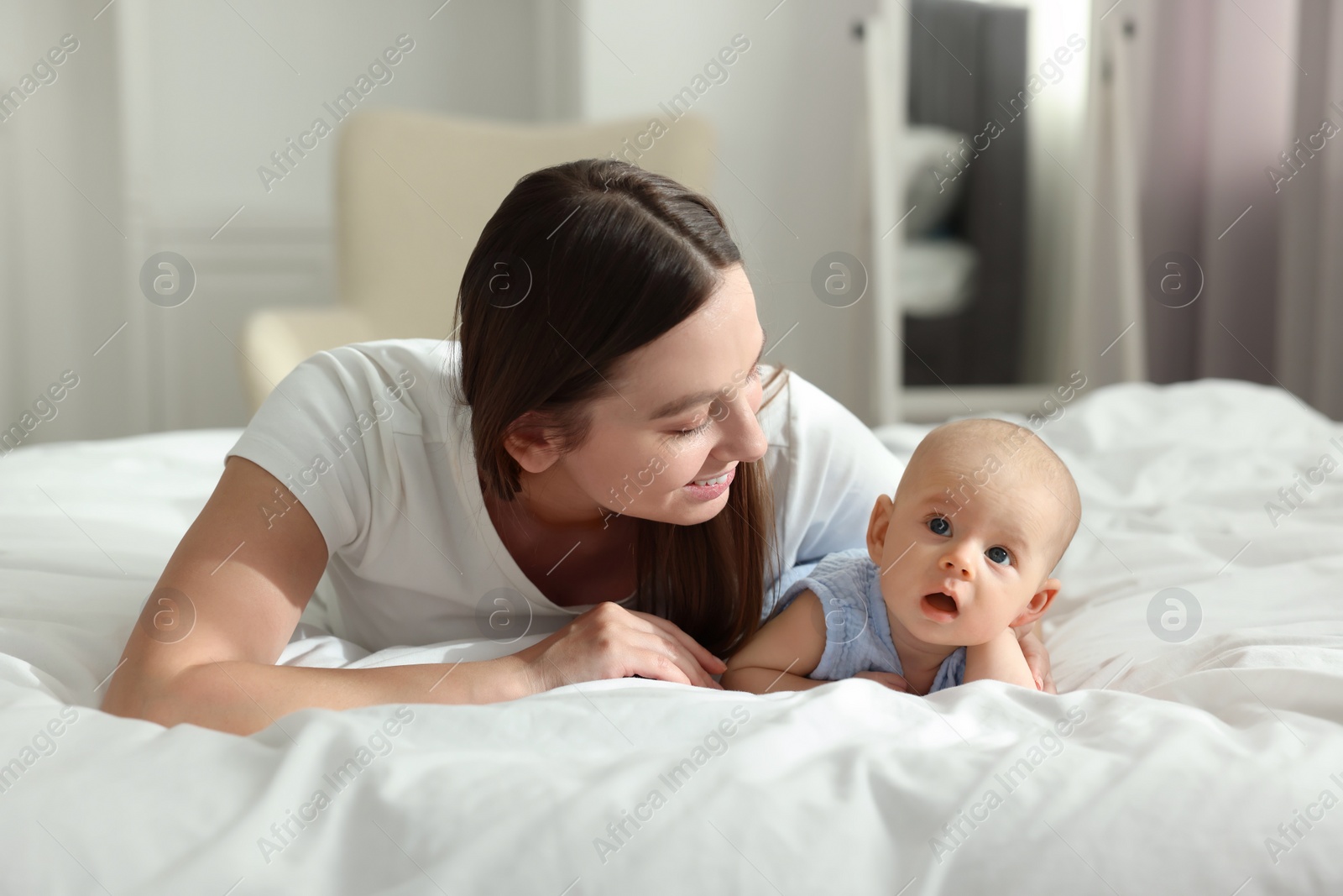 Photo of Mother with her cute baby on bed indoors