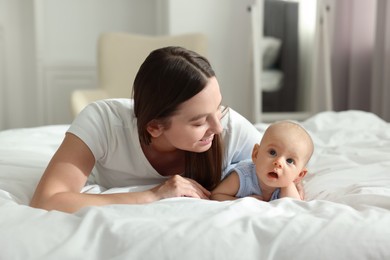 Mother with her cute baby on bed indoors