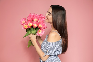 Photo of Portrait of beautiful smiling girl with spring tulips on pink background. International Women's Day