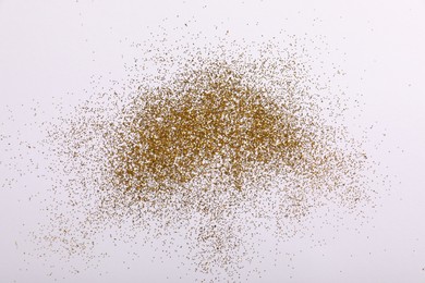 Photo of Shiny golden glitter on white background, top view