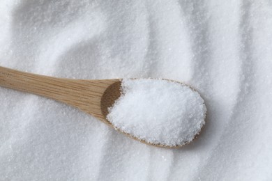 Photo of Wooden spoon on white sea salt, above view