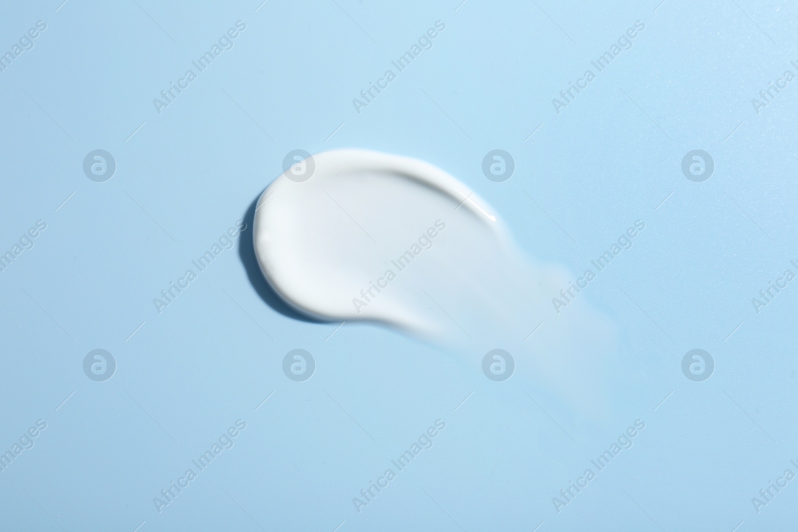 Photo of Sample of face cream on light blue background, top view