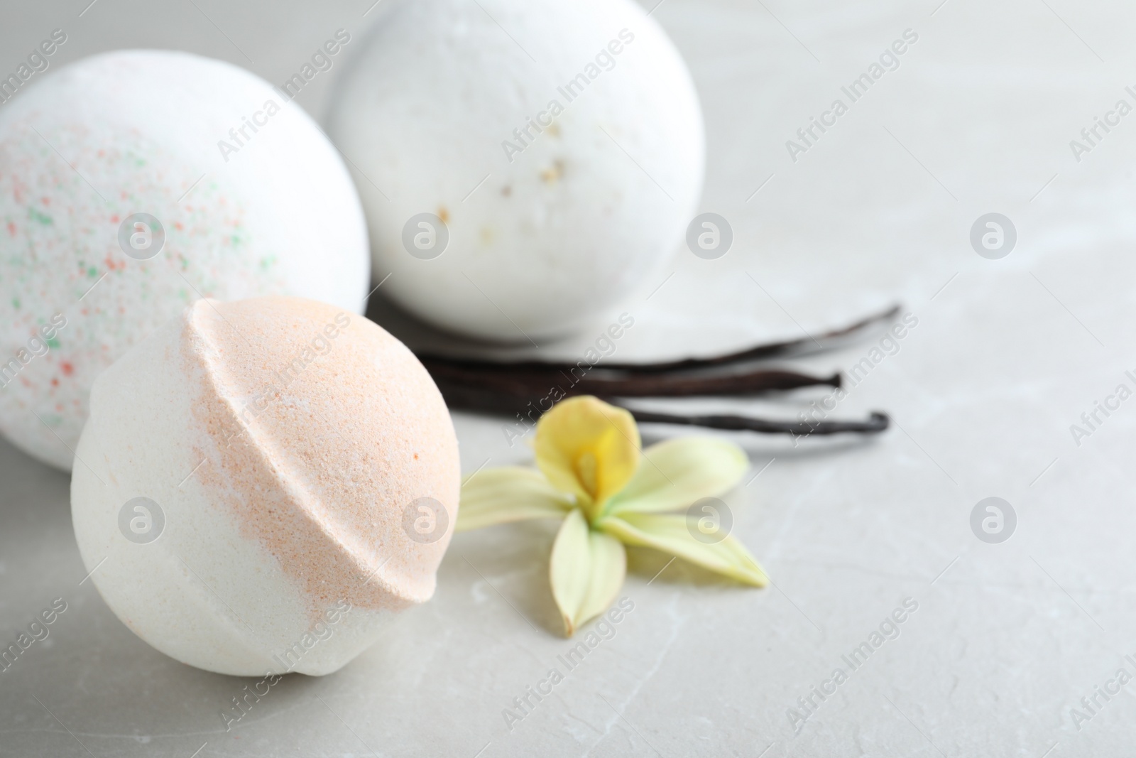 Photo of Fragrant bath bombs, vanilla sticks and flower on light grey table, closeup