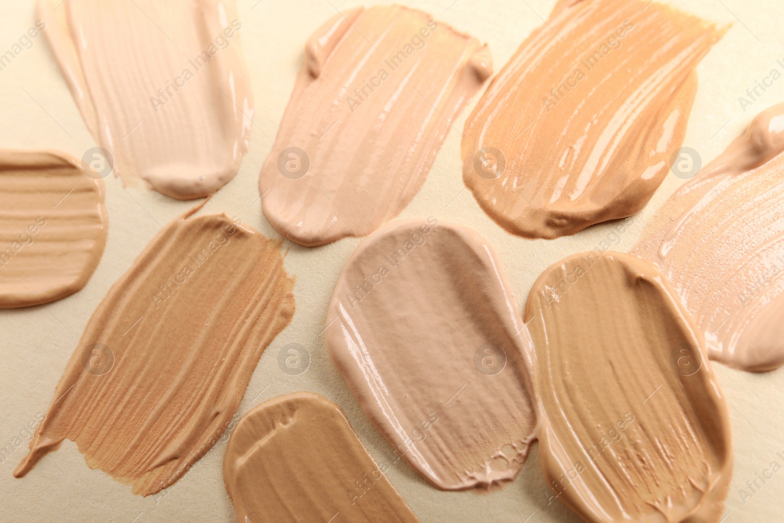 Photo of Samples of skin foundation on beige background, closeup