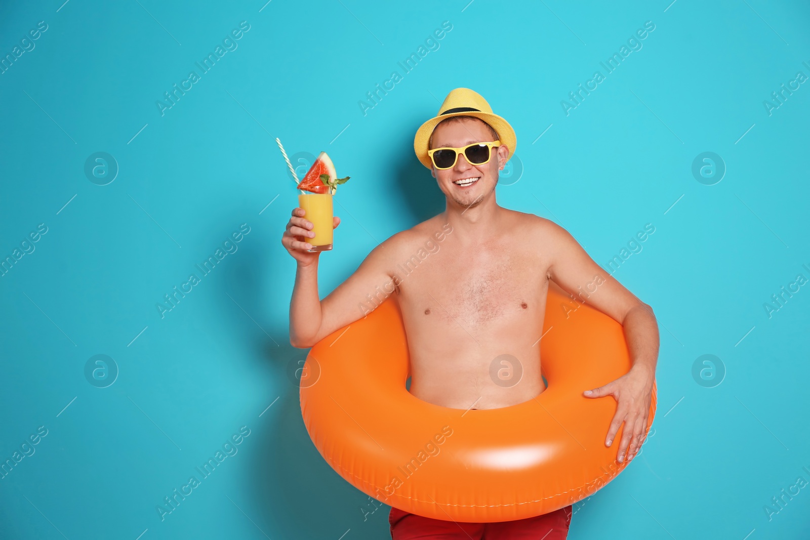 Photo of Shirtless man with inflatable ring and glass of cocktail on color background