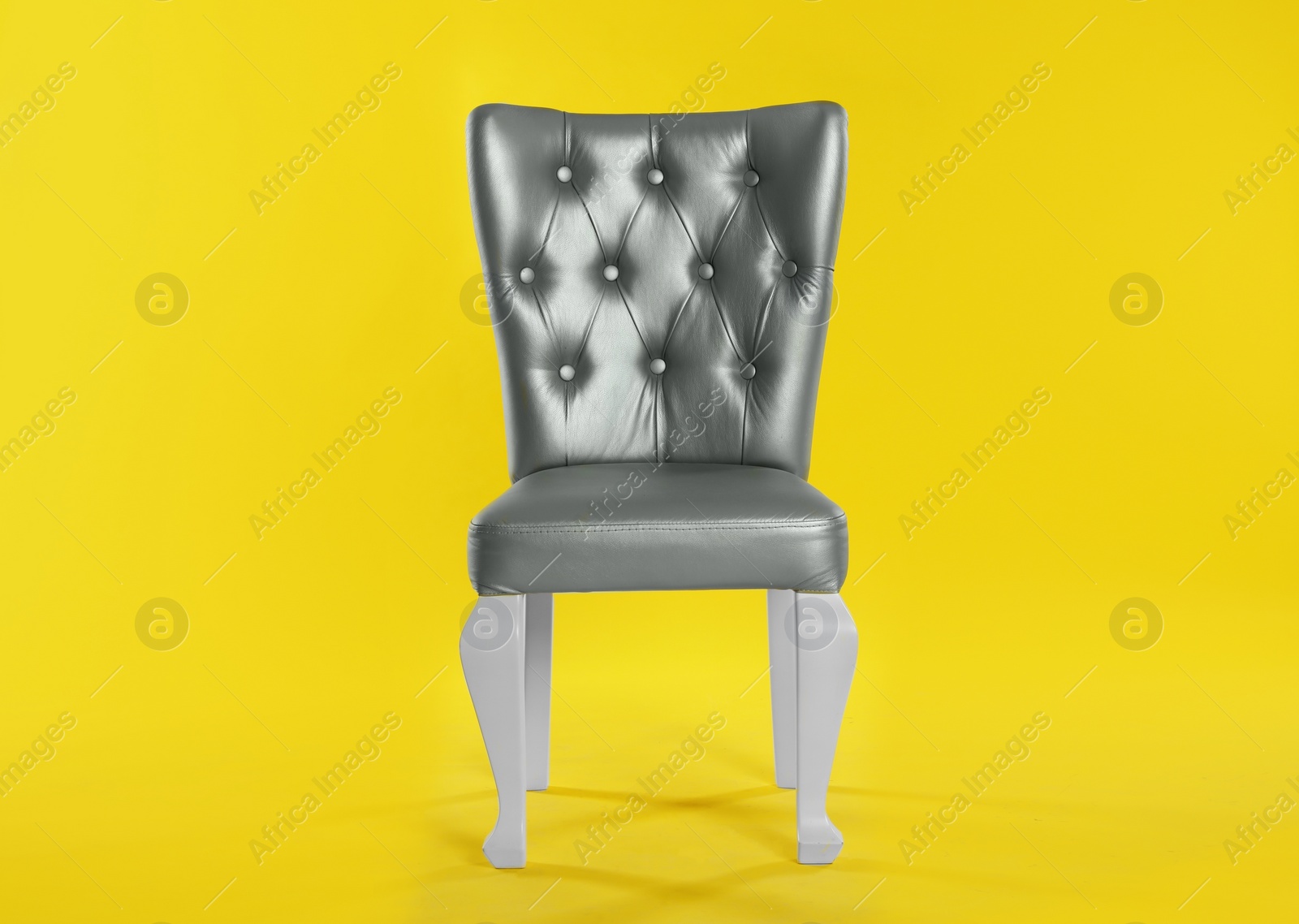 Photo of Stylish silver chair on yellow background. Element of interior design