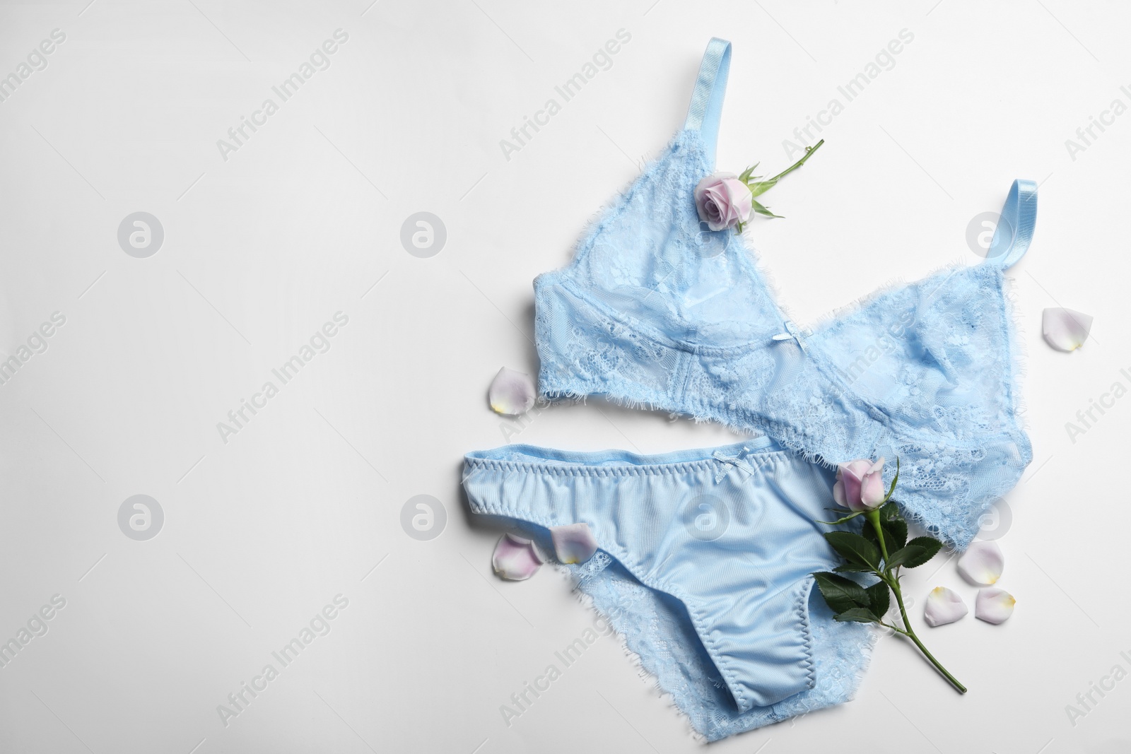 Photo of Elegant women's underwear and rose flowers on white background, flat lay