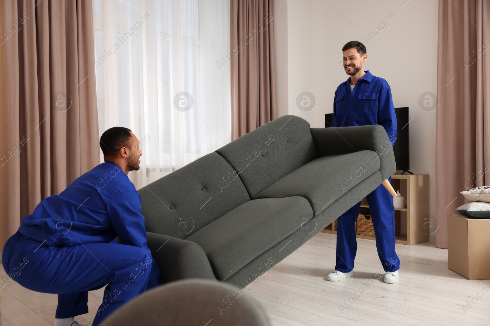 Photo of Male movers carrying sofa in new house