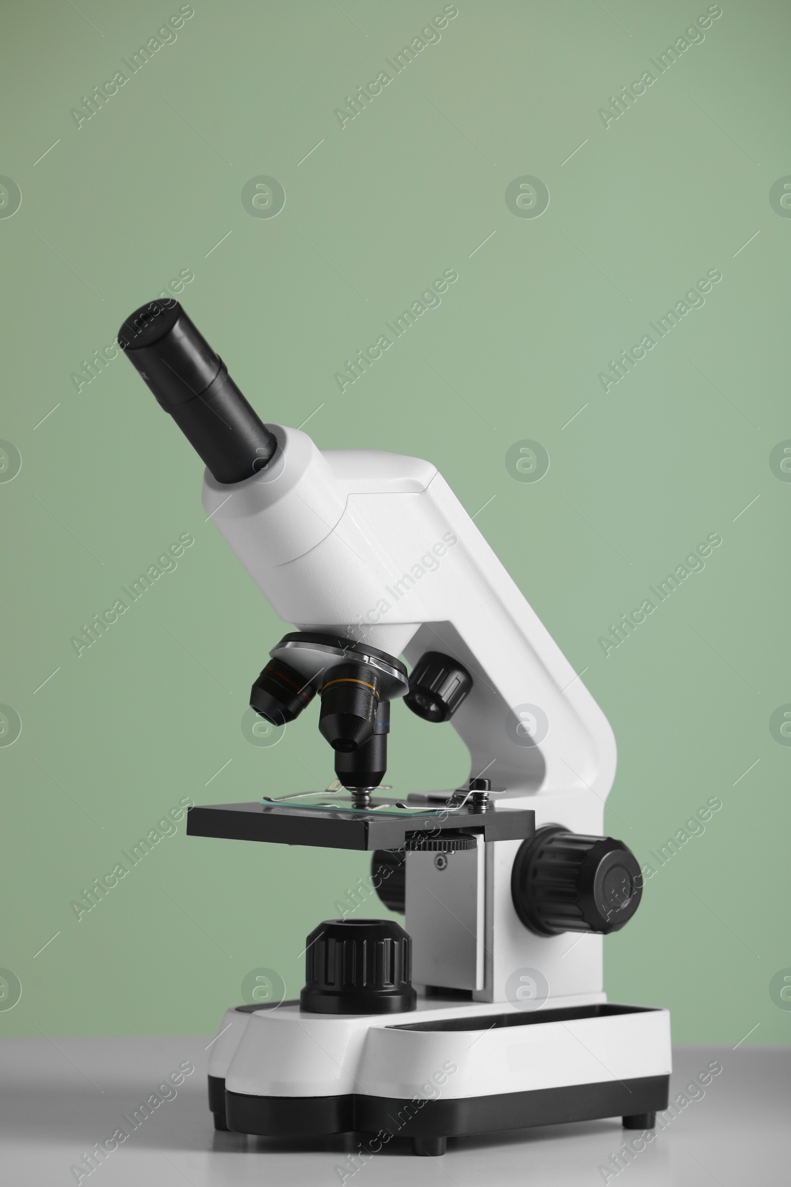 Photo of Modern microscope on table against green background