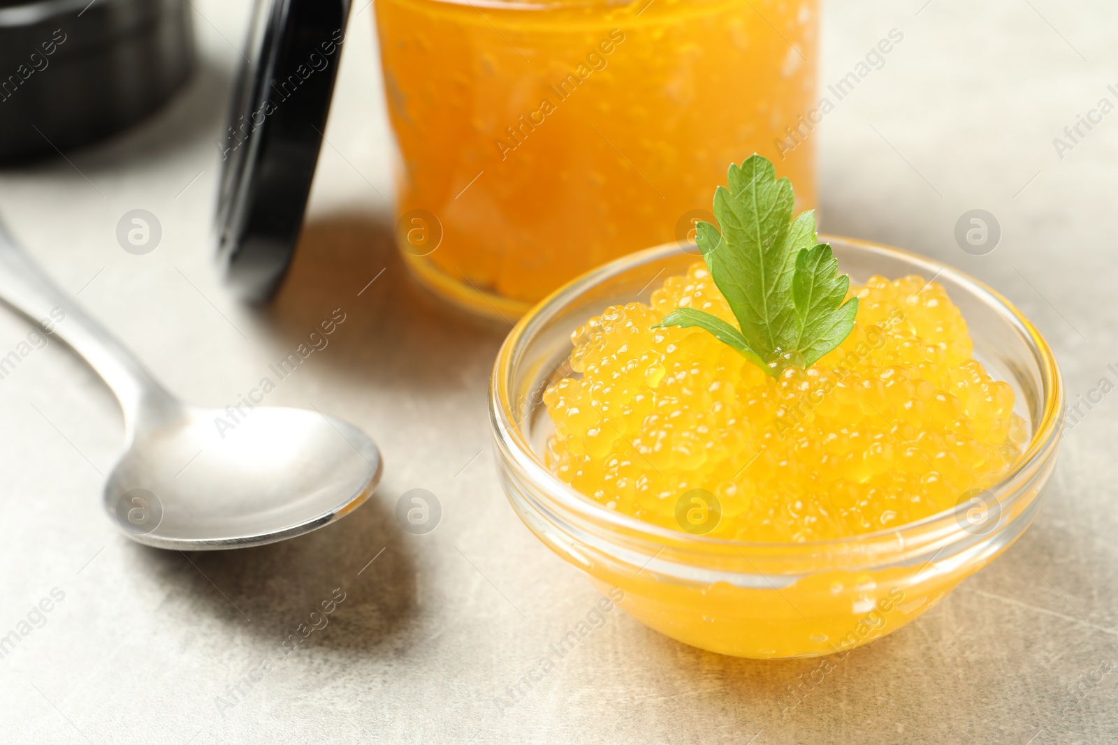 Photo of Fresh pike caviar in bowl, parsley and spoon on light grey table, closeup