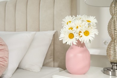 Photo of Bouquet of beautiful daisy flowers on nightstand in bedroom, space for text