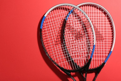 Photo of Tennis rackets on red background, flat lay. Sports equipment