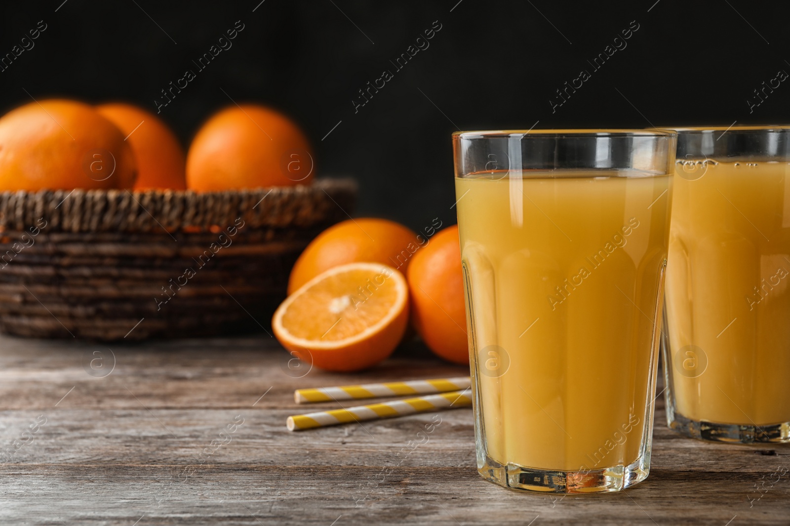 Photo of Glasses of orange juice and fresh fruit on wooden table. Space for text