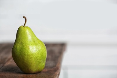 Ripe pear on wooden table against blurred background. Space for text