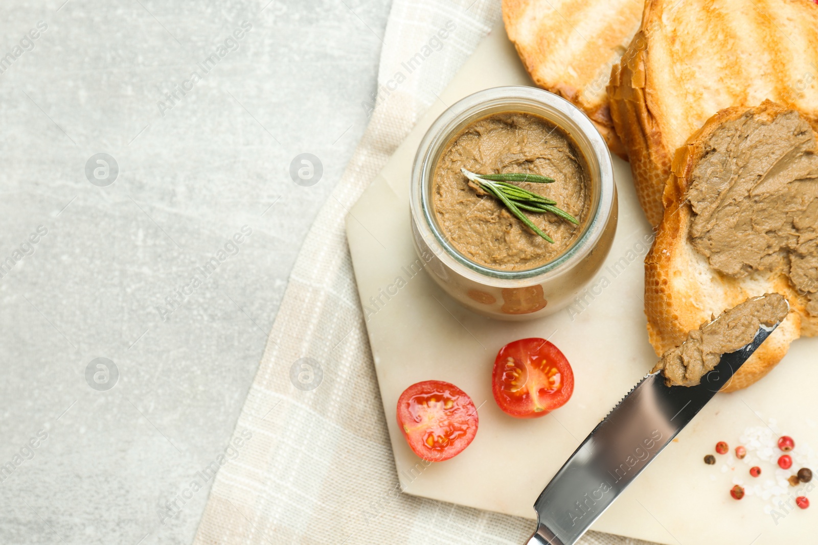 Photo of Tasty liver pate, bread and tomatoes on light grey table, top view. Space for text