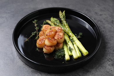 Photo of Delicious fried scallops with asparagus and thyme on grey table