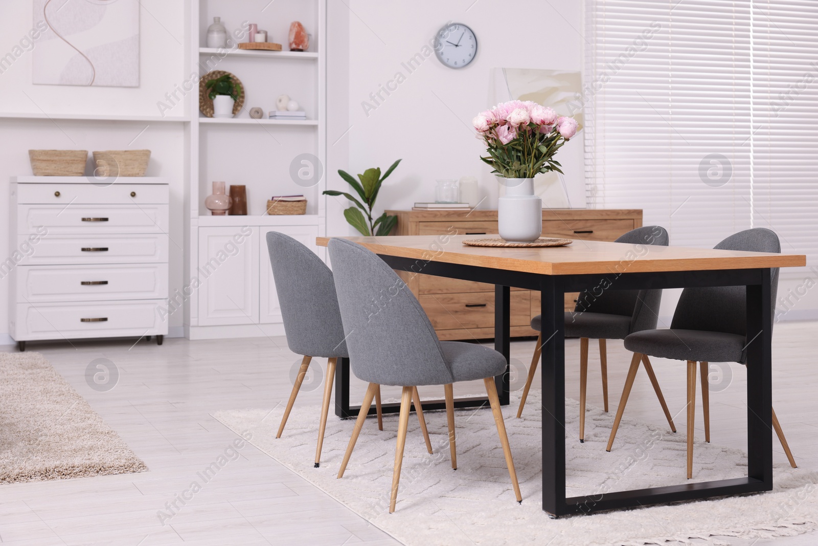 Photo of Stylish dining room with cosy furniture and flowers