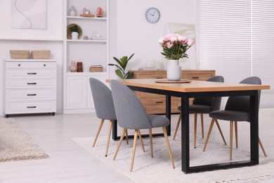 Photo of Stylish dining room with cosy furniture and flowers