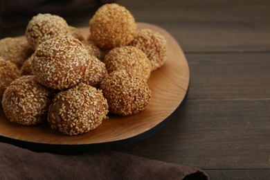 Photo of Many delicious sesame balls on wooden table, closeup. Space for text