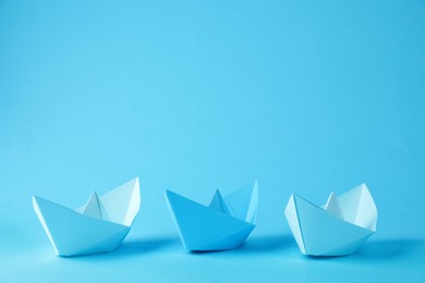 Handmade paper boats on light blue background.  Space for text