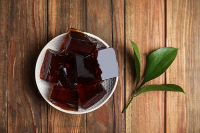 Photo of Delicious grass jelly cubes on wooden table, flat lay