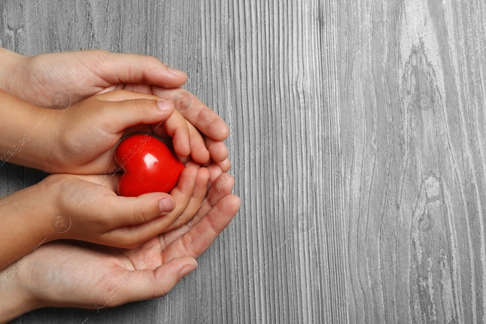 Photo of Woman and child holding heart on wooden background, top view with space for text. Donation concept