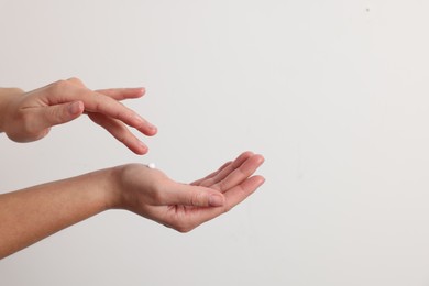 Woman applying cosmetic cream onto hand on white background, closeup. Space for text