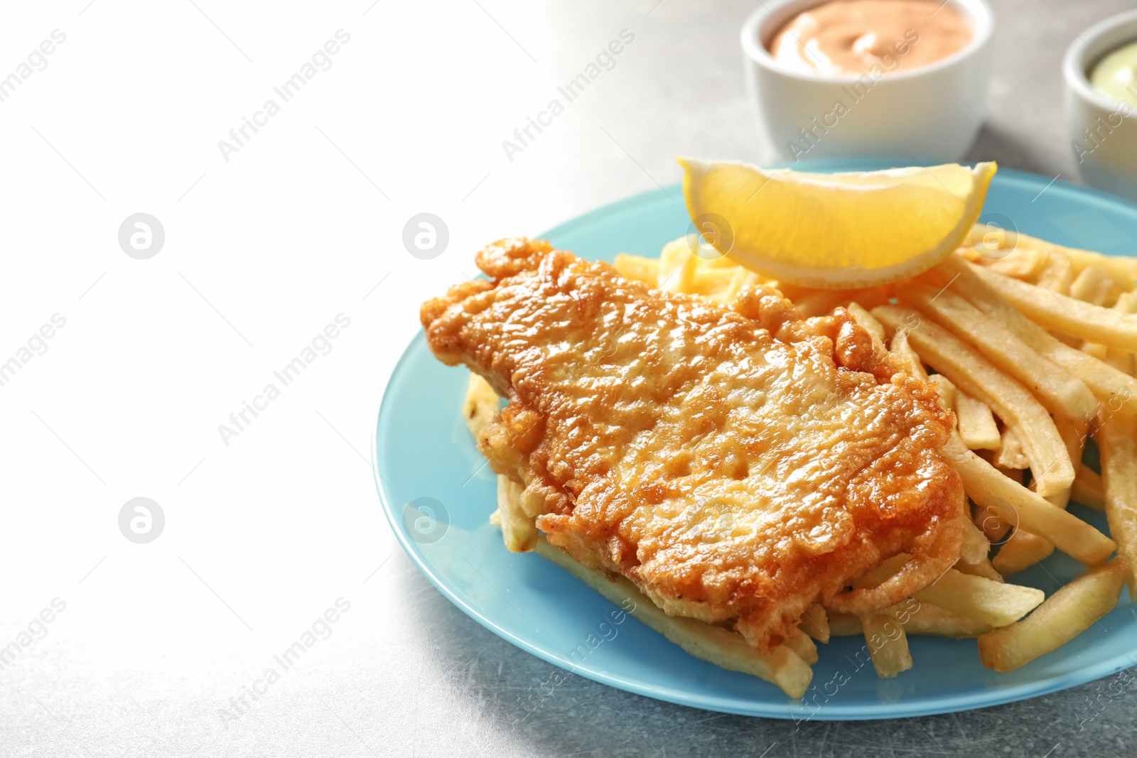 Photo of Plate with British Traditional Fish and potato chips on grey background. Space for text