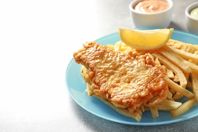 Photo of Plate with British Traditional Fish and potato chips on grey background. Space for text