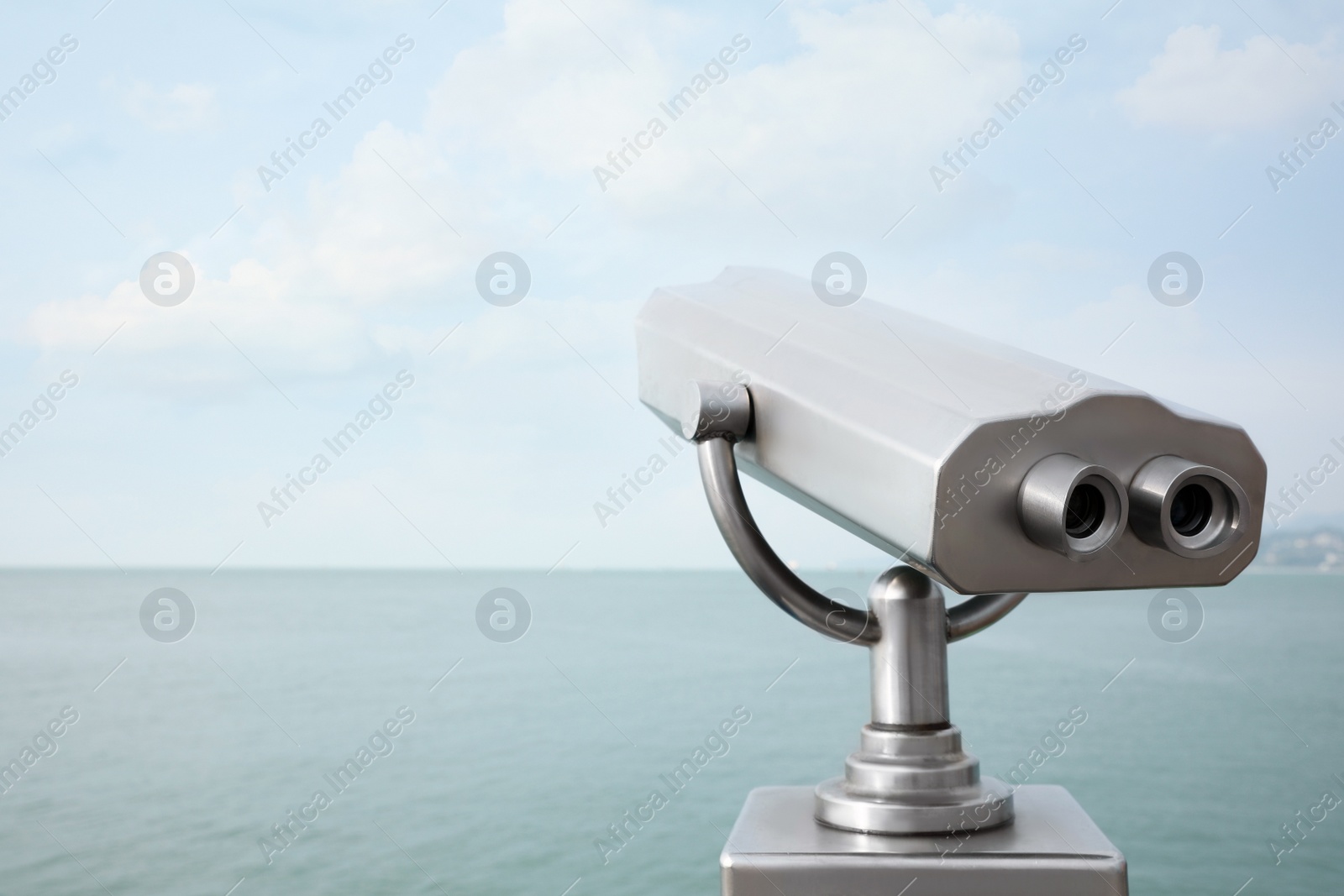 Photo of Metal tower viewer installed near sea, space for text. Mounted binoculars