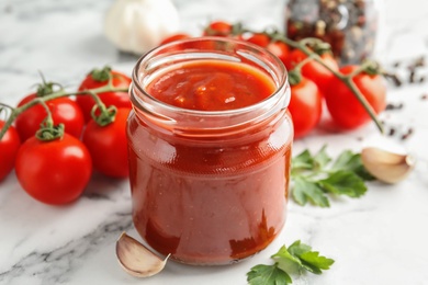 Photo of Composition with jar of tasty tomato sauce on marble table, closeup
