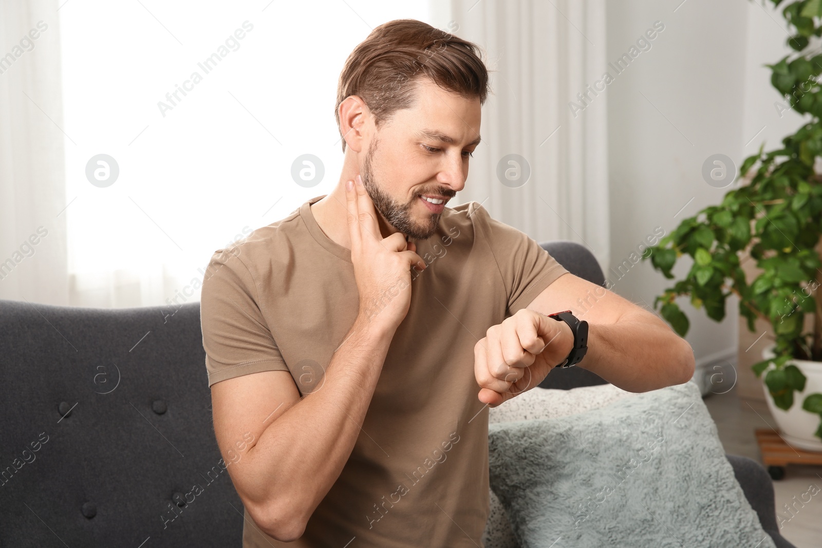 Photo of Man checking pulse with fingers at home