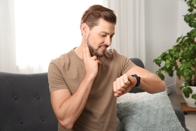 Photo of Man checking pulse with fingers at home