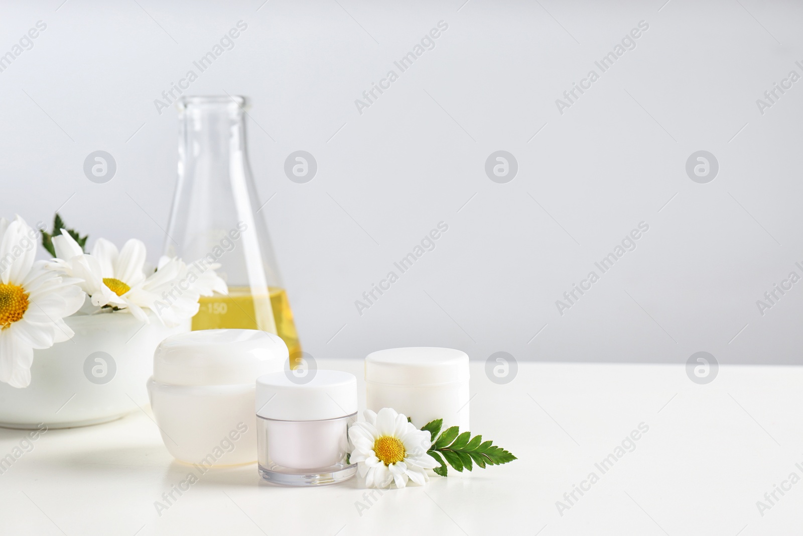 Photo of Skin care products, ingredients and laboratory glassware on table, space for text. Dermatology research