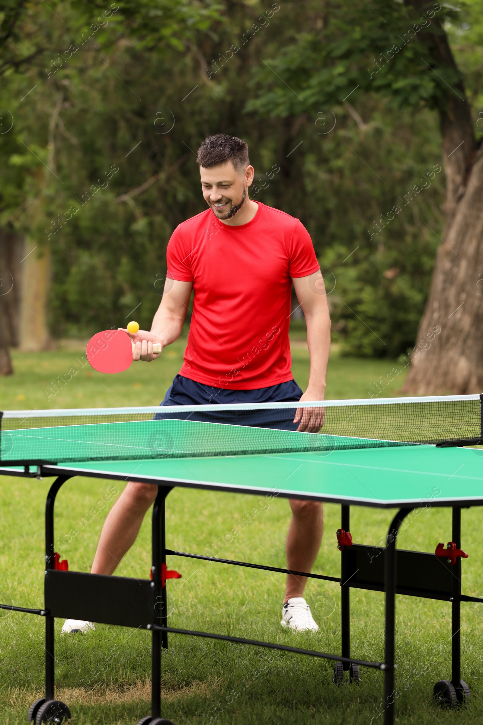 Photo of Happy man playing ping pong outdoors on summer day