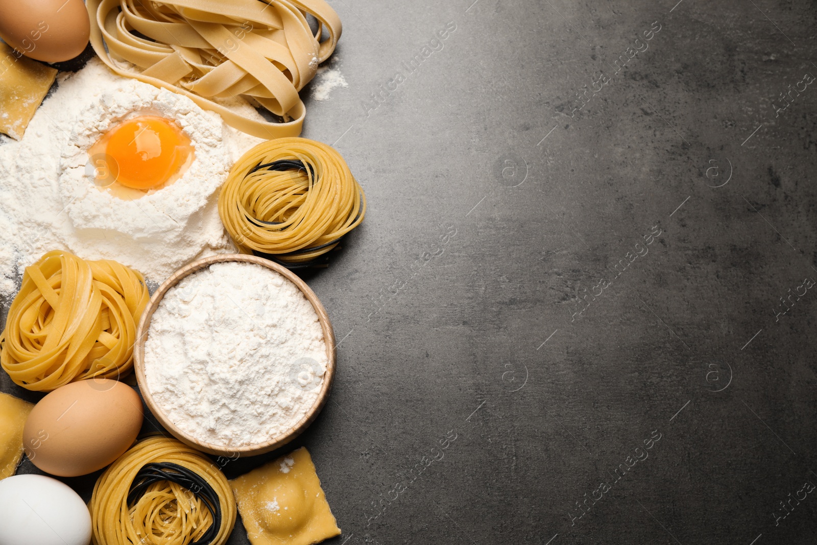 Photo of Flat lay composition with different types of pasta on grey table. Space for text