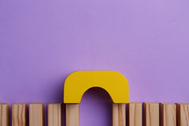 Photo of Bridge made of wooden blocks on violet background, flat lay with space for text. Connection, relationships and deal concept