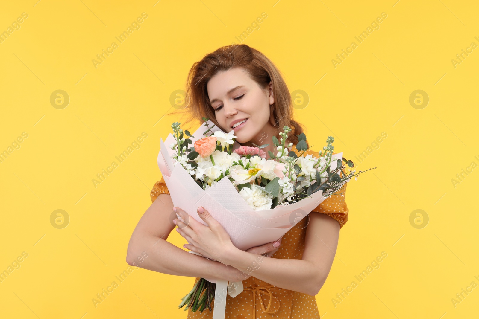 Photo of Happy woman with bouquet of beautiful flowers on yellow background