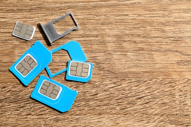 Photo of Different SIM cards and tray on wooden background, flat lay. Space for text