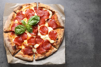 Tasty pepperoni pizza with basil on grey table, top view. Space for text