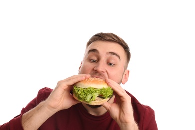 Photo of Young man eating tasty burger on white background