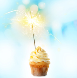 Birthday cupcake with sparkler on light background